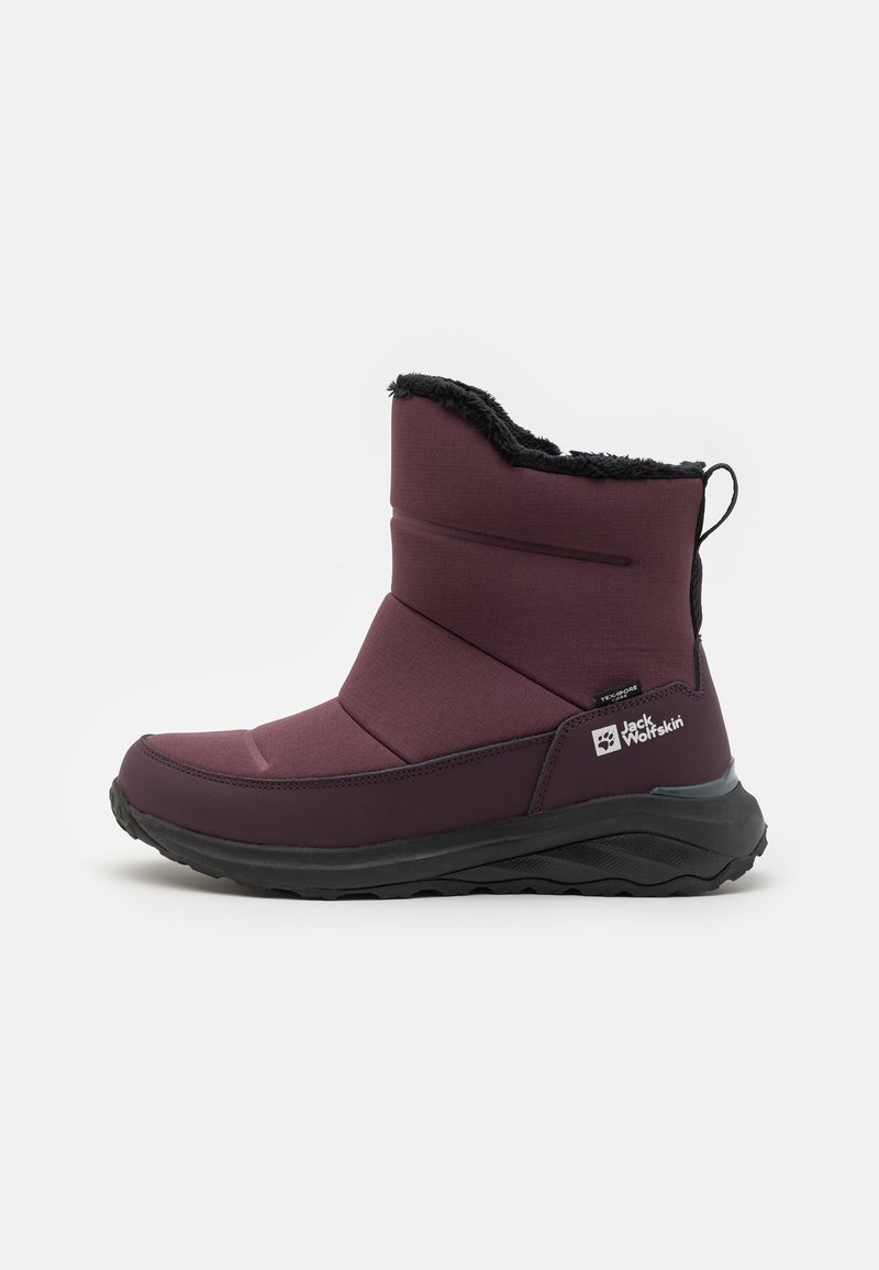 Botte d'hiver mi-hauteur de couleur marron rouge avec doublure en fourrure noire, semelle épaisse noire, languette de traction au talon, et logo Jack Wolfskin sur le côté du talon.