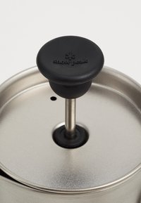 Presse à café en acier inoxydable avec un bouton en silicone noir. Comprend une tige centrale en acier inoxydable et une finition métallique lisse.