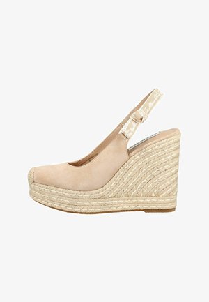 Espadrille compensée en daim beige avec semelle plateforme en jute tressé et bride arrière en tissu ornée de texte en écriture blanche.