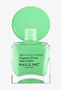 Grön glasnagellackflaska med ett runt, matt lock. Etiketten har text om växtbaserade ingredienser och vegansk formulering.