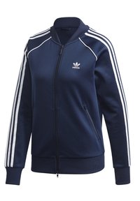Námořnická modrá treková bunda Adidas s bílými pruhy na rukávech, zipovým předním dílem, dvěma zipovými kapsami a logem Adidas na levé straně hrudi.