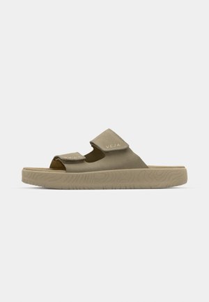 Sandalias beige con dos correas de Velcro, parte superior suave tipo ante, suela gruesa y texturizada, y diseño minimalista que presenta el logotipo "VEJA."