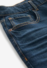 Donkerblauwe spijkerbroek van denim met oranje stiksel, met een voorzakdetail, een gladde textuur en een getailleerde pasvorm.