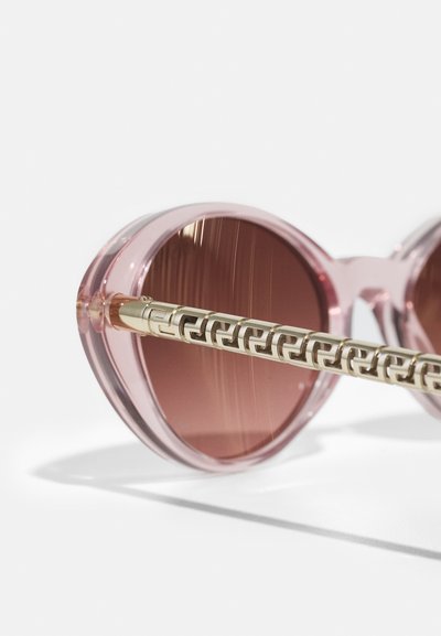 Pink-tinted sunglasses with round lenses, transparent pink frames, and a gold-patterned temple accent. Smooth texture and sleek design.