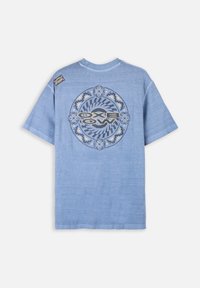 T-shirt a maniche corte in cotone blu con un design grafico circolare in blu scuro e bianco, con il nome del brand "OXBOW" al centro.