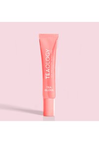 Tube brillant de couleur corail étiqueté "TEA GLOSS" par TEAOLOGY. Texture lisse avec un design compressible et un capuchon arrondi.