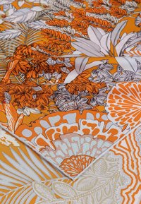 Mehrfarbiger Stoff mit einem orangefarbenen Hintergrund und floralem Muster in Grautönen, Weiß und Creme, strukturierte Oberfläche, geschichtetes Design.