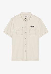 Camicia beige a maniche corte con cuciture nere, due tasche sul petto e un logo. Presenta un colletto classico e una chiusura con bottoni.