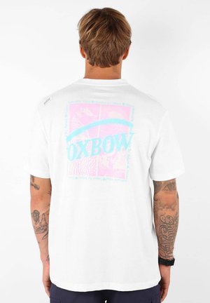 T-shirt blanc à manches courtes avec un graphisme coloré au dos, portant le texte "OXBOW" en bleu, rose et divers motifs.
