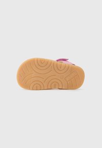 Sandal infantil con un upper de un vibrante color rosa y una suela de goma naranja texturizada, que presenta patrones circulares y una impronta del logo.