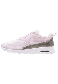 Zapatilla Nike con parte superior de malla rosa claro, acentos de ante gris, suela blanca y amortiguación visible en el talón.