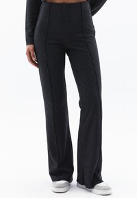 Donkergrijze flared broek van een zachte, gestructureerde stof met verticale stikdetails. Heeft een hoge tailleband en een relaxed fit.