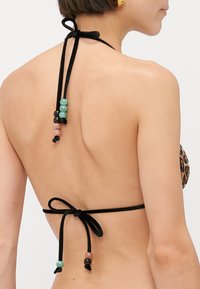 Haut de bikini noir à halter avec liens ajustables. Décoré de perles multicolores en vert, noir et rose le long des bretelles.