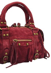 Sac à main en daim rouge avec quincaillerie en laiton, doté de poignées tressées, de poches zippées et de clous décoratifs. Texture douce avec une forme structurée.