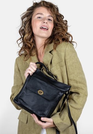 Schwarze Lederhandtasche mit einer äußeren Vordertasche, runder Form, kurzen Griffen und einem abnehmbaren Schultergurt. Weitere Texturdetails sind sichtbar.