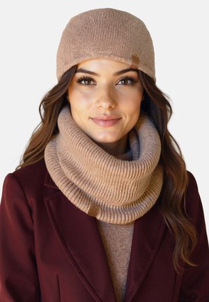 Pletená béžová čepice s ohrnutým okrajem, doplněná o odpovídající pružný nákrčník. Oba kusy mají jemnou texturu a značkovou nálepku.