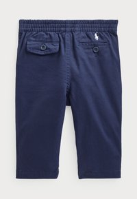 Námořnické bavlněné kalhoty s elastickým pasem, dvěma zadními kapsami a malým vyšitým logem na přední straně. Hladký povrch, rovný střih.