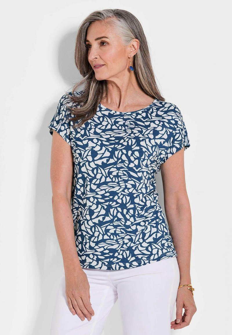 Kurzärmeliges navy-blaues T-Shirt mit einem weißen Blättermuster, rundem Halsausschnitt und weichem Stoff, kombiniert mit weißen Hosen.