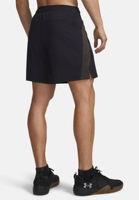 Μαύρο αθλητικό σορτς με γκρι υφασμάτινη πλευρική επένδυση, ελαστική μέση και σκισίματα στη βάση· συνδυασμένο με μαύρα αθλητικά παπούτσια με υφή.