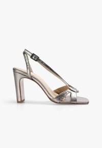 Metallic sølv højhælede sandaler med firkantet tå, ankelstrop og chunky hæl. Glat tekstur og minimalistisk design med tværgående stropper.