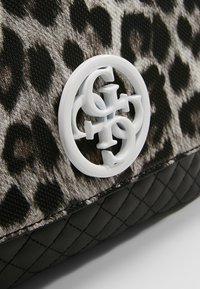 Tkanina s leopardím potiskem a hladkou texturou, s bílým logem. Spodní část tvoří černá prošívaná kůže.