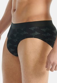 Černé slipy s geometrickým vzorem, vyrobené z hladkého materiálu s měkkým pasem, poskytující přiléhavou siluetu.
