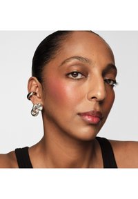 Zilveren oorknoppen in een gedraaide ontwerp met een parelaccent. Gladde textuur met een gepolijste afwerking, gedragen aan het linkeroor.