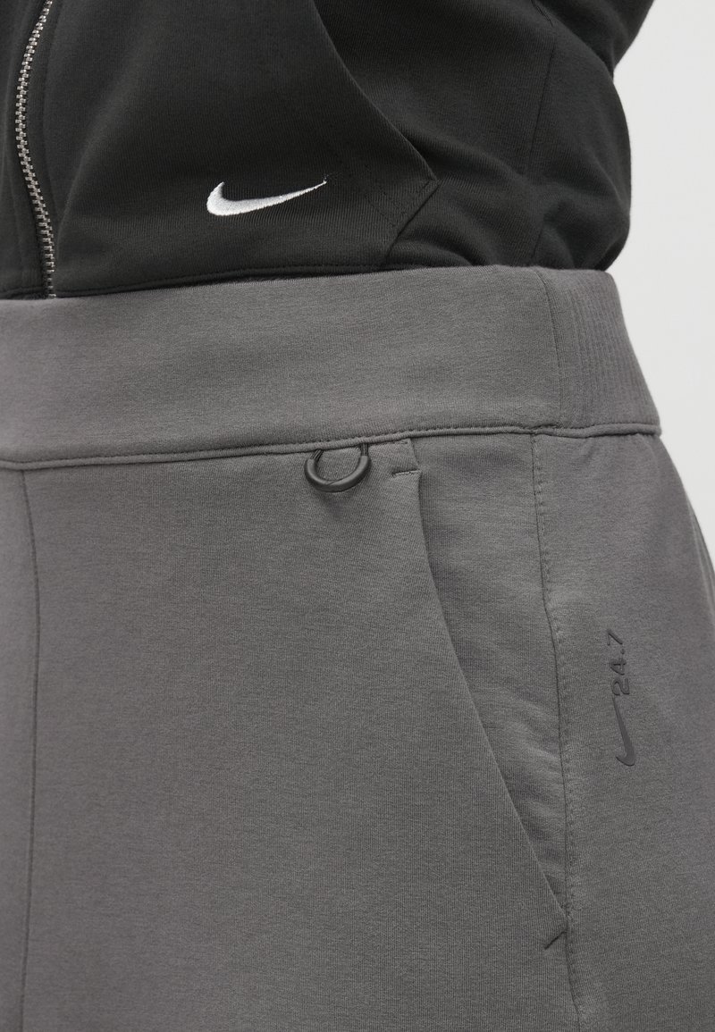 Pantalons de survêtement gris en tissu doux, dotés d'une taille sans couture, de poches latérales et d'un accent de logo sombre sur la jambe.
