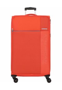 Valise à coque souple rouge avec une finition texturée, poignées de transport supérieures, poignee télescopique et quatre roues pivotantes noires. Comprend une poche zippée.