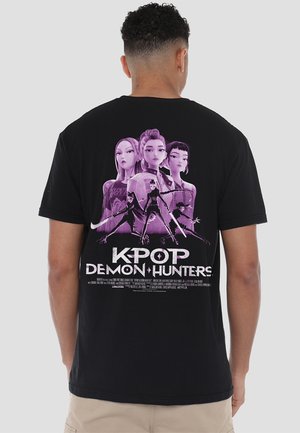 Schwarzes Baumwoll-T-Shirt mit einem großen grafikdruck in lila und weiß von K-Pop-Charakteren mit dem Titel "KPOP DEMON HUNTERS" auf dem Rücken.