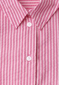 Vaaleanpunavalkoraidallinen nappikiinnitteinen paita, joka on leveäkauluksinen ja siinä on kaksi näkyvää valkoista nappia.