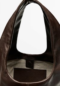 Sac à main en cuir texturé brun foncé avec une large poignée, intérieur en tissu beige et petite poche en cuir à l'intérieur.