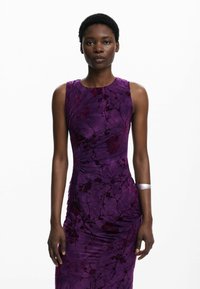 Robe violette à la silhouette ajustée, motif floral et tissu texturé. Présente un design sans manches et des fronces sur les côtés.