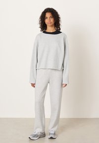 Helehall hall pusa ja sobivad püksid, valmistatud pehmest kangast, mugava lõikega, laiade varrukatega ja lihtsa disainiga.