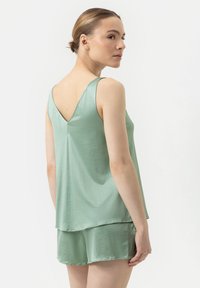 Muntgroene lounge set met een mouwloze top met V-rug en bijpassende shorts. Gemaakt van een gladde, lichte stof.