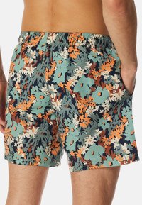 Bloemmotief zwembroek met een meerkleurig ontwerp in teal, oranje en marineblauw. Gemaakt van lichtgewicht stof met een elastische tailleband en zijzakken.