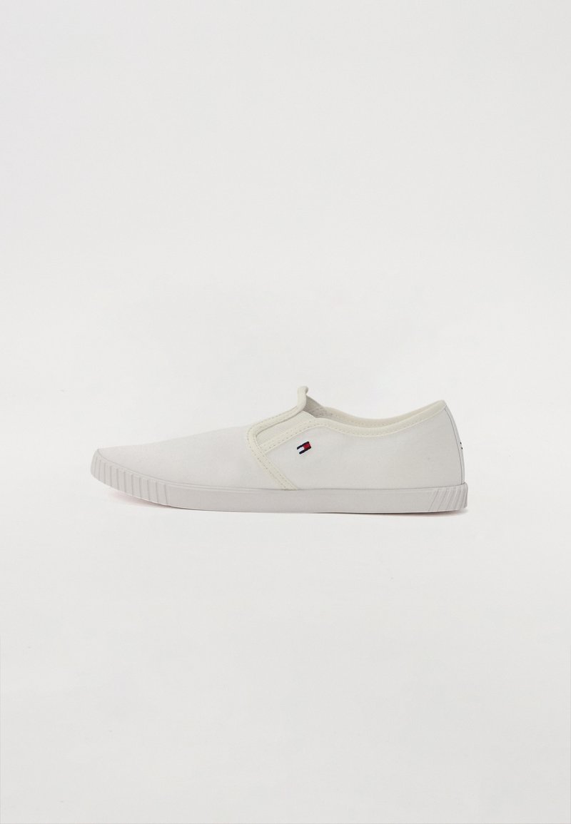 Baskets blanches sans lacets avec semelle en caoutchouc et petit logo Tommy Hilfiger sur le côté, vues de profil sur fond blanc.