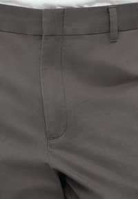 Γκρι υφασμάτινο παντελόνι με απαλό υλικό, διαθέτοντας επίπεδη πρόσοψη, θηλιές για ζώνη και διακριτικές ορατές ραφές κατά μήκος των ραφών.