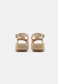 Sandalias de esparto en color beige claro con suelas de cuerda trenzada, correas ajustables en el tobillo, tacón plano y detalles de tela tejida.