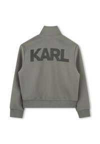 Grijze sweatshirt met hoge kraag en ribgebreide manchet, met grote zwarte stippen tekst "KARL" op de rug, gladde textuur en getailleerd ontwerp.