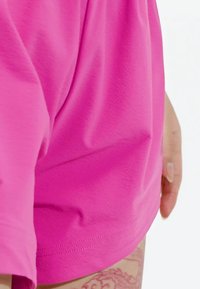 Svetle růžová krátká košile s krátkým rukávem vyrobená z texturované látky, volného střihu, s přímým lemem a jednoduchými švy.
