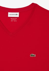 Rød bomulds T-shirt med V-udskæring. Har et lille broderet grønt krokodillelogo på brystet. Regular fit.