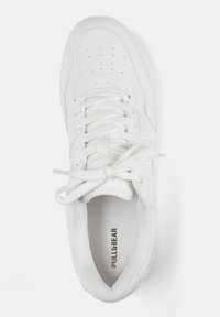 Białe sportowe sneakersy wykonane z gładkiej skóry, z okrągłym noskiem, sznurowanym zapięciem i perforowanymi detalami na wierzchu.