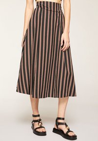 Svart och rostrandig midikjol med en figursydd midja, flödande silhuett och sidoklyfta. Matchad med svarta remsandaler.