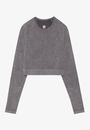 Šedý žebrovaný dlouhý rukáv crop top s raglánovými rukávy. Má kulatý výstřih a lem, který končí nad pasem.