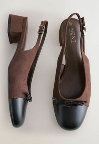 Rudos zomšiniai slingback batai su juodu odiniu pirštu, papuošti mažomis kaspino detalėmis ir mažu blokiniu kulnu. Iš viso glotni tekstūra.