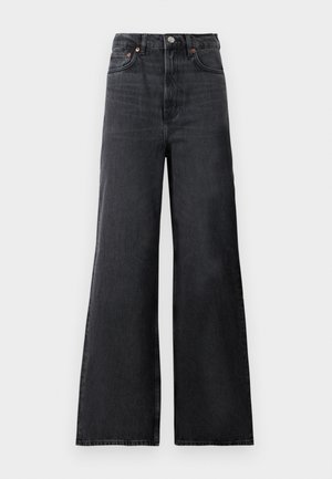 Jean en denim noir évasé avec taille haute, présentant une fermeture à bouton en métal, des poches avant et un léger dégradé sur le tissu.