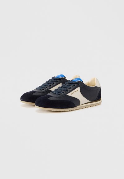 Παπούτσια σνίκερς από σουέντ σε ναυτικό μπλε με λεπτομέρειες σε ανοιχτό κρεμ και υφασμένους τόνους. Διαθέτουν στρογγυλεμένη μύτη, κορδόνια σε αντίθεση και λαστιχένια σόλα.