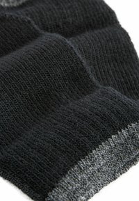 Tejido de punto negro texturizado con un patrón ondulado, que presenta una banda gris contrastante en el borde. Material suave y flexible.