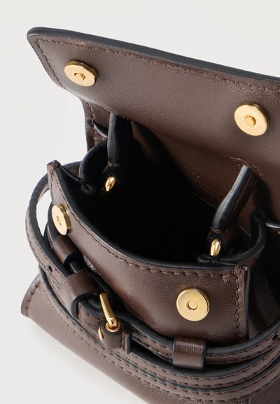 Καφέ δερμάτινη γυναικεία τσάντα με χρυσά κουμπώματα, μαύρο εσωτερικό και ιμάντα με αγκράφα, εμφανίζεται ανοιχτή από επάνω γωνία.
